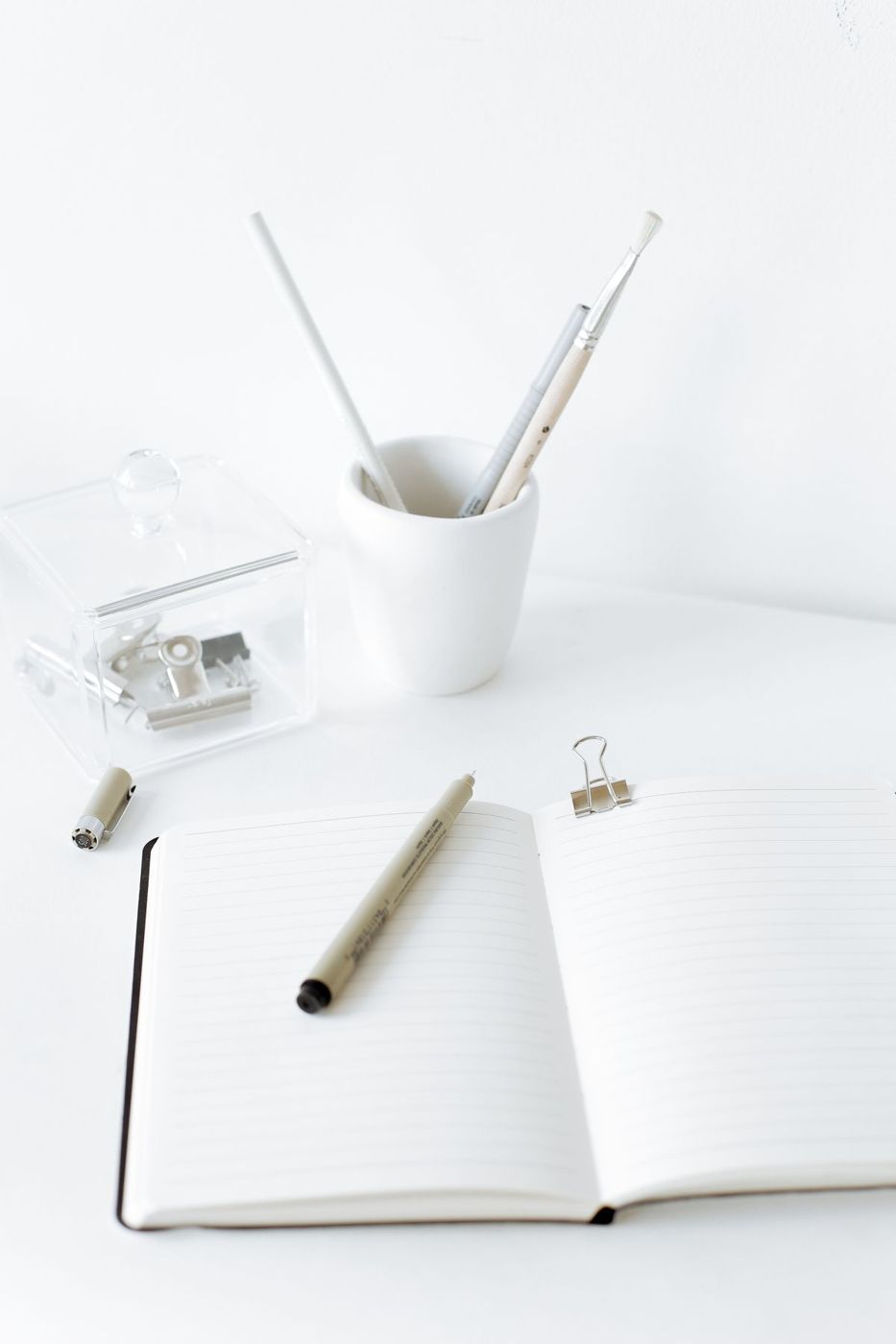 Notebook, pens and office stationery on a white desk